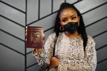 African american woman wearing black face mask show Ecuador passport in hand. Coronavirus in America country, border closure and quarantine, virus outbreak concept.