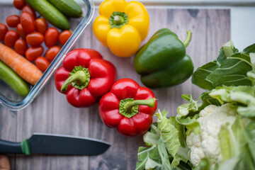Fresh and colorful bell peppers and other vegetables on wooden table