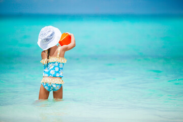 Adorable little girl playing with beach toys on white tropial beach