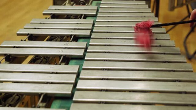 A young guy playing the vibraphone at a music school.