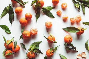 Oranges fruits composition with green leaves and slice on white wooden background, top view