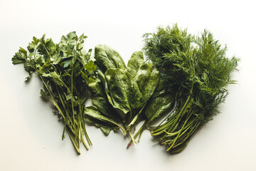 Flying spinach, parsley and dill leaves over white background. Image.