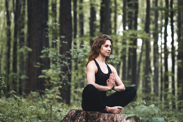 Young girl practices yoga in the forest, the concept of enjoying privacy and concentration, sunlight - 394700769