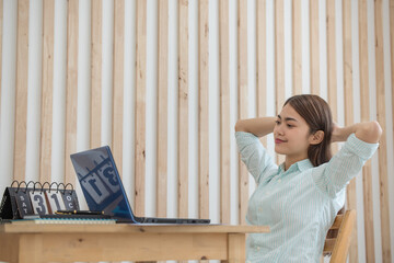 Asian businesswoman working with laptop and enjoy relaxing with hands behind her head while working at her house, working at home, business concept