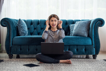 Young Asian woman enjoy listening to music with headphones and using laptop, happy and relaxing time