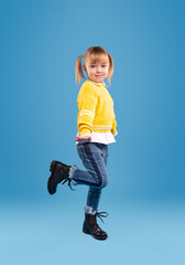 Little girl in warm clothes jumping in studio