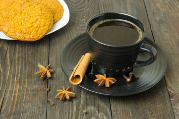 Obraz na płótnie Canvas A cup of coffee, cinnamon, star anise, cloves and cookies on the table. Composition with coffee.