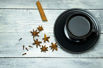 A cup of coffee, cinnamon, star anise, cloves on the table. Aromatic coffee with spices. Composition with coffee.