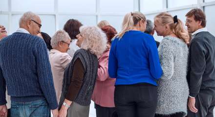 a group of old people standing with their backs indoors