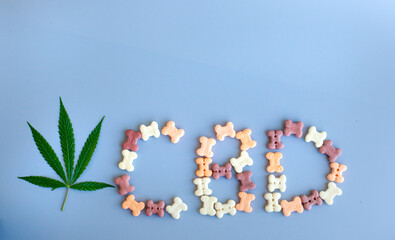 Marijuana leaves CBD cannabis written on a blue background for advertising. The green hemp or cannabis leaf and CBD lettering are written from pet food.