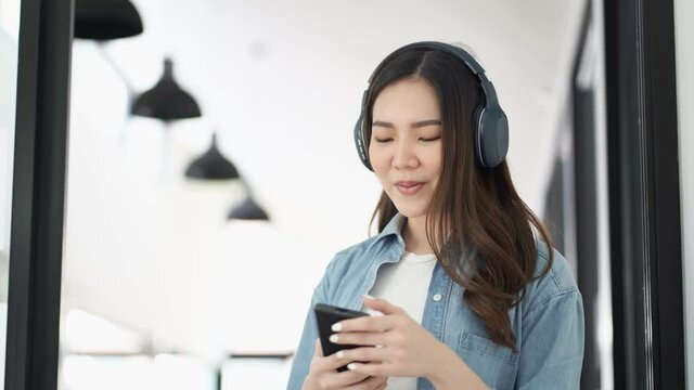 Asian woman using smart phone and headset singing a song.