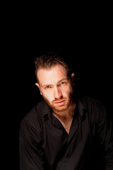 Fototapeta premium A man on a black background .Aggressive facial expression. Criminal personality