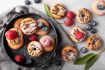 small homemade donuts with chocolate and berries on a gray plate, top view