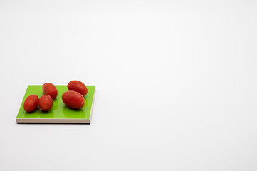tomatoes on colored coasters and white background