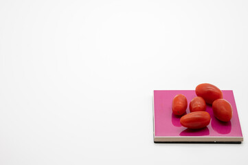 tomatoes on colored coasters and white background