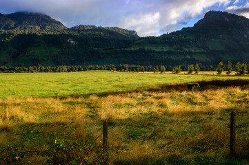 Day in the early morning with the sun rising. Humid and clear day. Dry grassland in the field with mountains in the background.