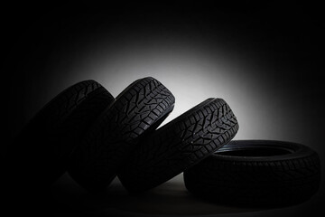 Stack of four new black tyres for winter car on black background © Angelov