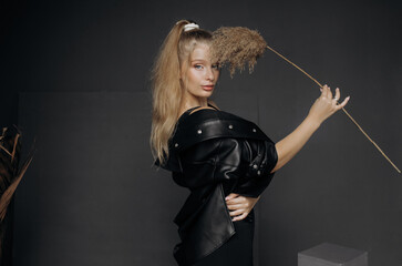 Portrait of a blonde woman in the studio with dry reed in her hand.
