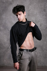 A young and masculine guy poses in a black sweater.