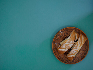 Pieces of pie with bird cherry filling decorated with powdered sugar on an antique handmade clay plate. Blue background with space for text, recipe. Top view, flat lay
