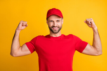 Photo of strong guy raise arms show muscles wear red t-shirt headwear isolated yellow color background