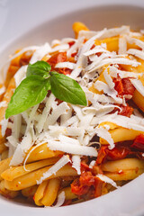 Casarecce pasta withe cherry tomatoes, parmesan cheese and fresh basil on white background. Close up