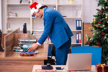 Young male employee celebrating Christmas at workplace