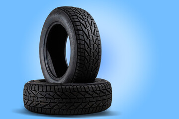 Stack of new black tyres for winter car on blue background