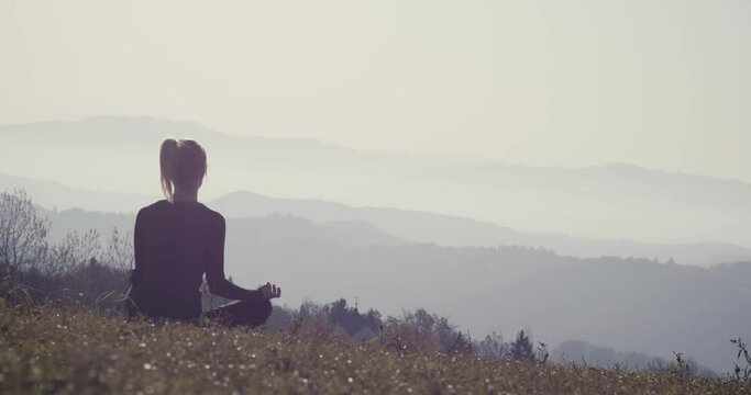 Young woman practice meditation pose on a view after autumn hiking