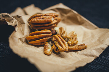 Raw walnuts on rustic paper with a dark background.