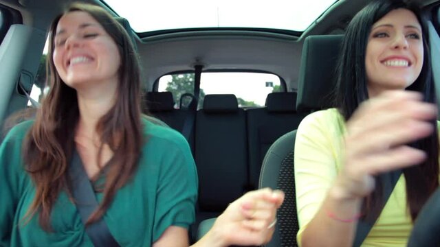 Two beautiful women dancing in car happy full of joy feeling freedom