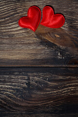 two red hearts on a dark wooden background, vertical top view