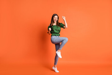 Fototapeta na wymiar Full length photo of shiny astonished lady dressed green off-shoulders blouse hands arms fists isolated orange color background