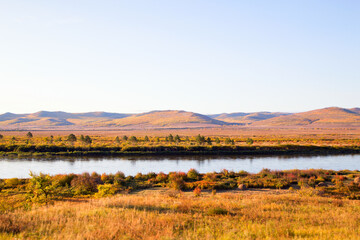  The river flows through the autumn forest. Horizontally.