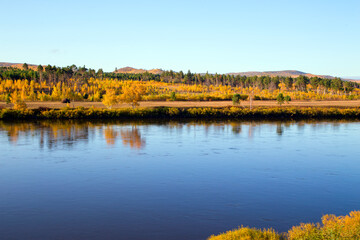  The river flows through the autumn forest. Horizontally.