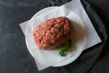 raw meatloaf on dark table background