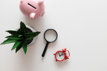 Freelance office workplace work concept. Red notebook, nature plant, alarm clock and pencils on a white minimalistic background with copy space.