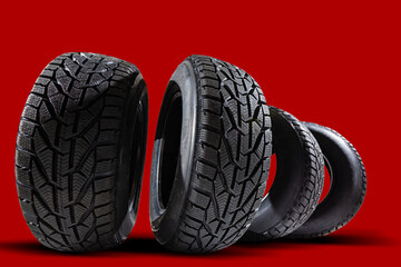 Stack of four new red tyres for winter car on blue background