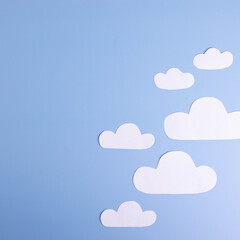 white paper clouds on plain light blue background. cope space