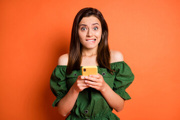 Photo of stressed woman hold telephone bite mouth wear dark shirt isolated on orange color...