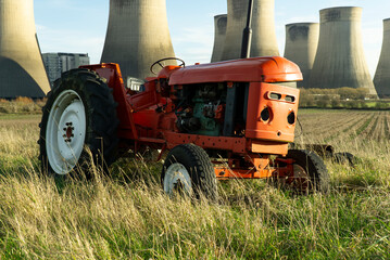 Small old red tractor abandoned in a field