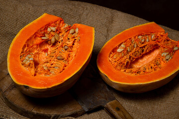 Cut ripe pumpkin. Nearby, the hatchet lies on a wooden board. Long pumpkin. Autumn vegetable.