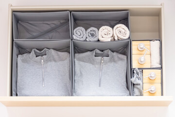 Drawer with things, gray sweaters, soap, hand towels and dispensers for liquid soap.