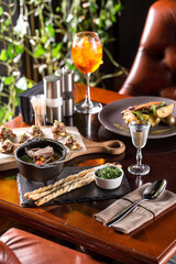 Shurpa soup with lamb in metal pot and vodka shot on wooden table at restaurant
