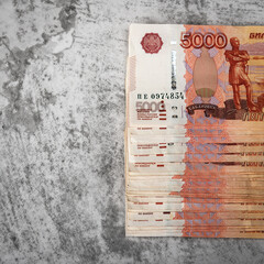 Russian cash banknotes of five thousand rubles, the bundle hangs on a gray background.