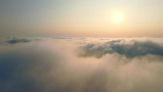 Flying over the clouds at sunset. The sun rises over the fog. Orange sunset over the fog.