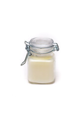 white candle in a glass jar on a white background
