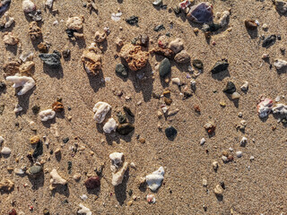 Fototapeta na wymiar many colorful stones on a sandy beach in the sun