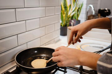 Caucasian young woman making pancakes at home kitchen