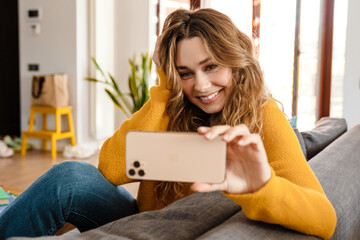 Happy beautiful girl smiling and taking selfie on cellphone